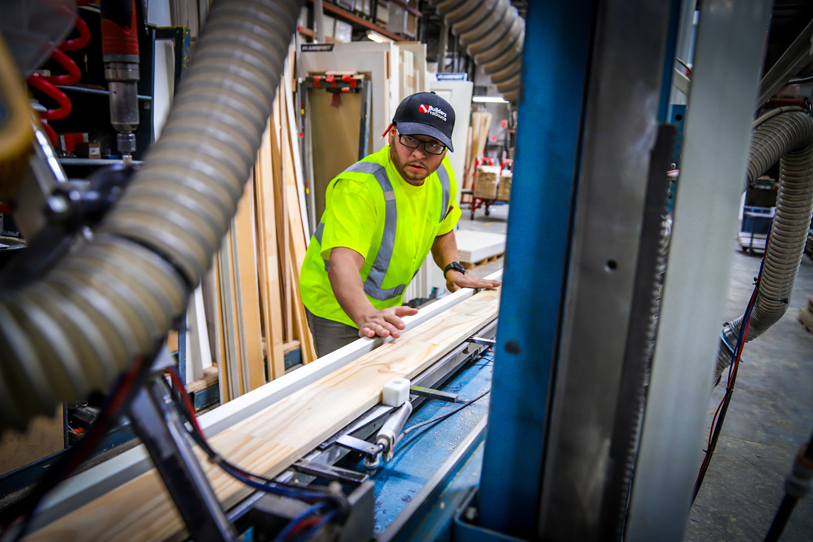Builders FirstSource employee guides a wood component through millwork equipment