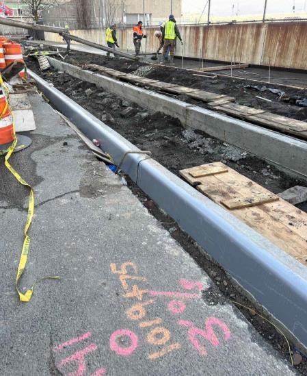 Active street reconstruction at the Sunset Park infrastructure project, with workers beside a newly formed curb