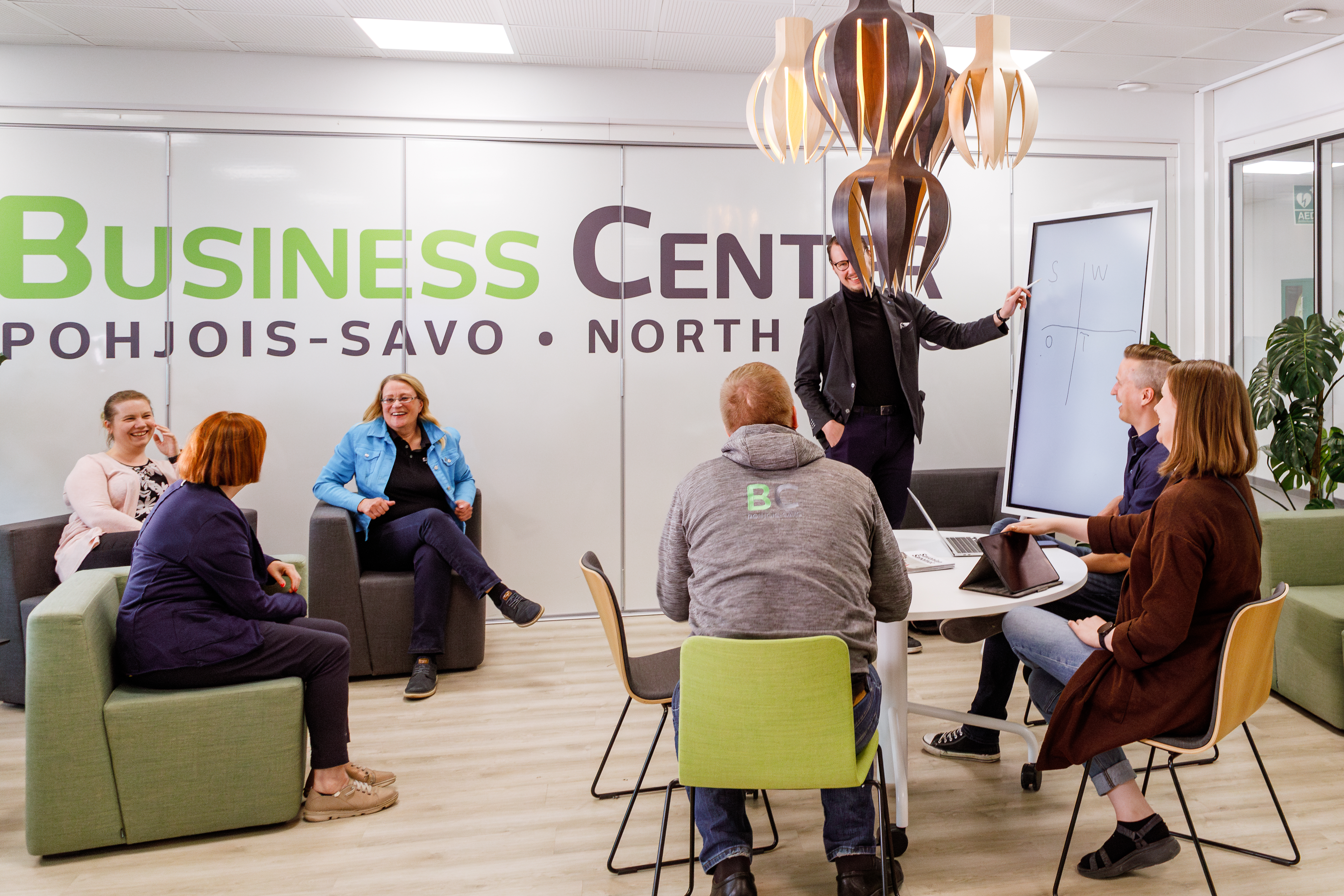 A Business Center group discussing a SWOT grid beside a whiteboard