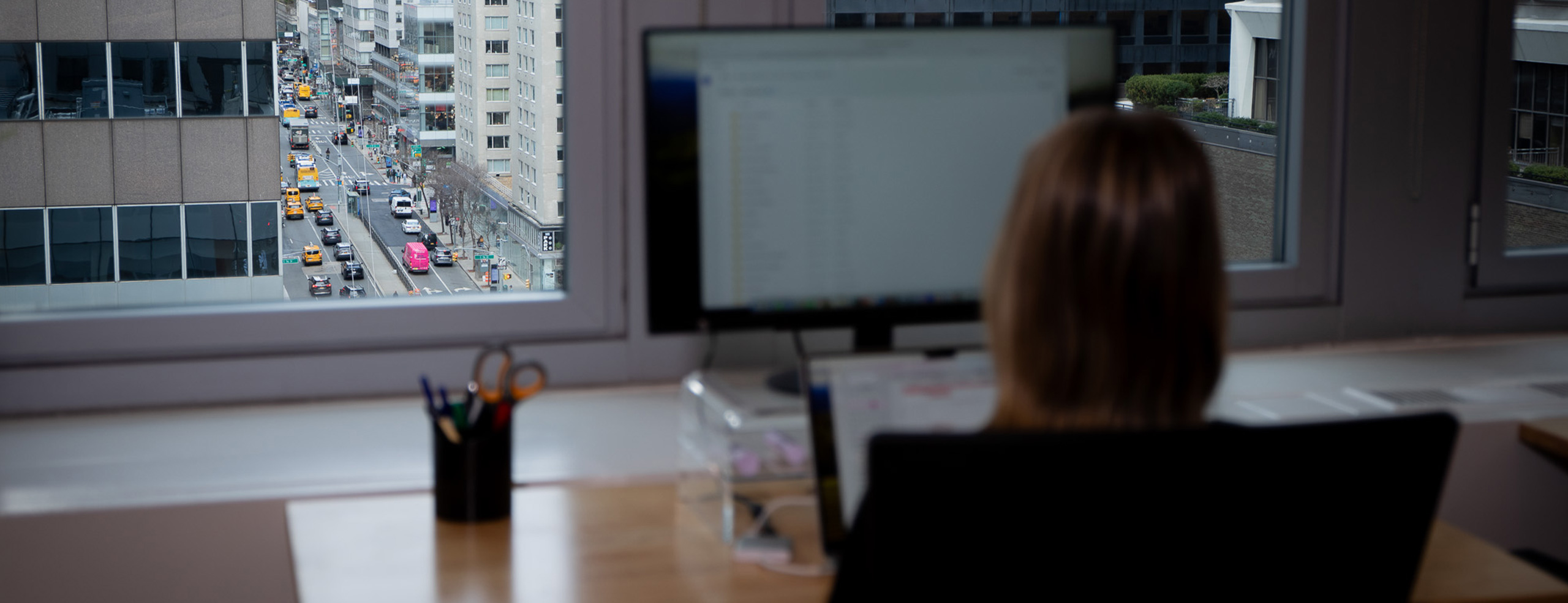 A C Street team member working beside a window overlooking Midtown Manhattan
