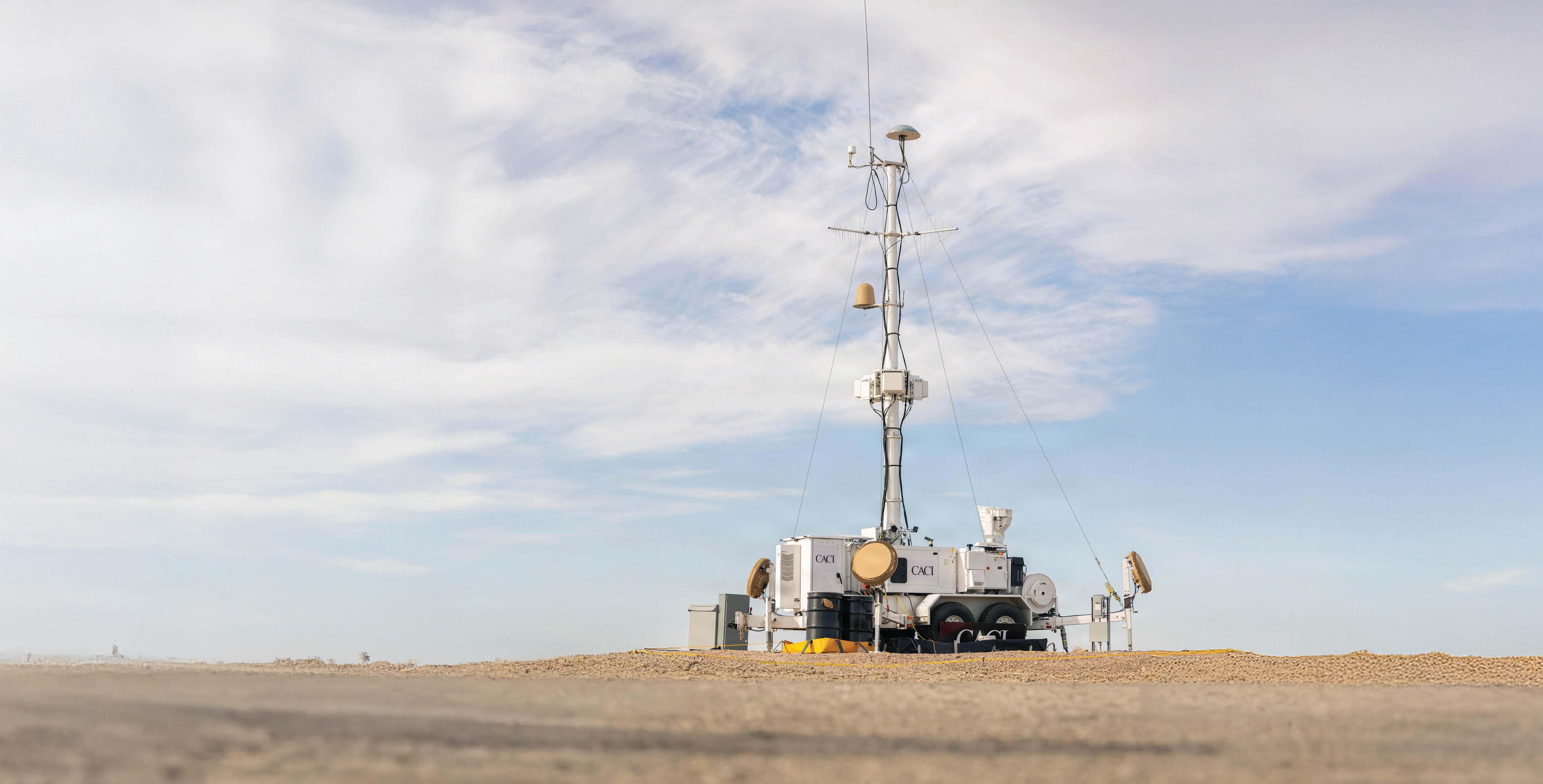 SkyValor trailer-mounted drone defense system with a tall antenna mast in a desert setting