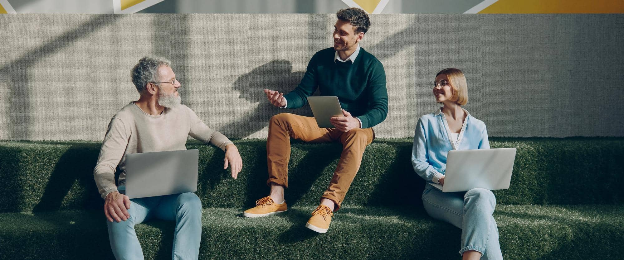 Three people with laptops talking on tiered seating in Caelius’s website photography