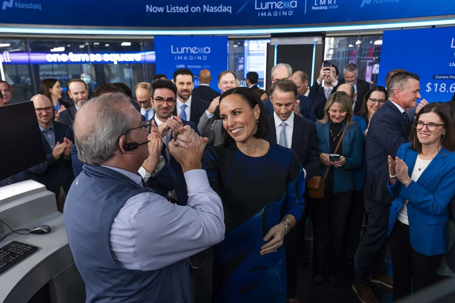 Caitlin Zulla smiling and greeting a Nasdaq representative as colleagues applaud at Lumexa Imaging’s December 2025 market debut