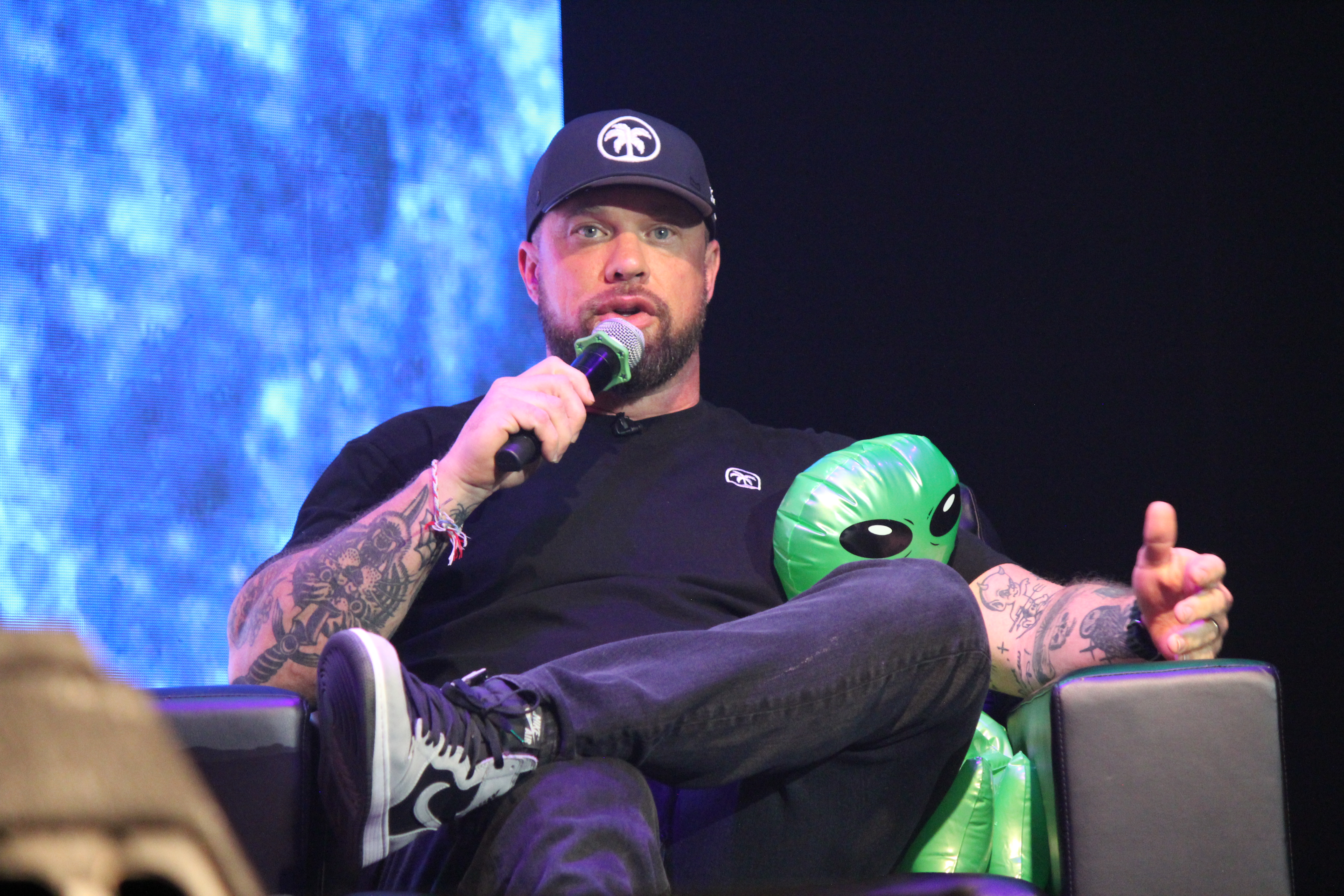Caleb Counts seated onstage speaking into a microphone at Walter Studios in Phoenix