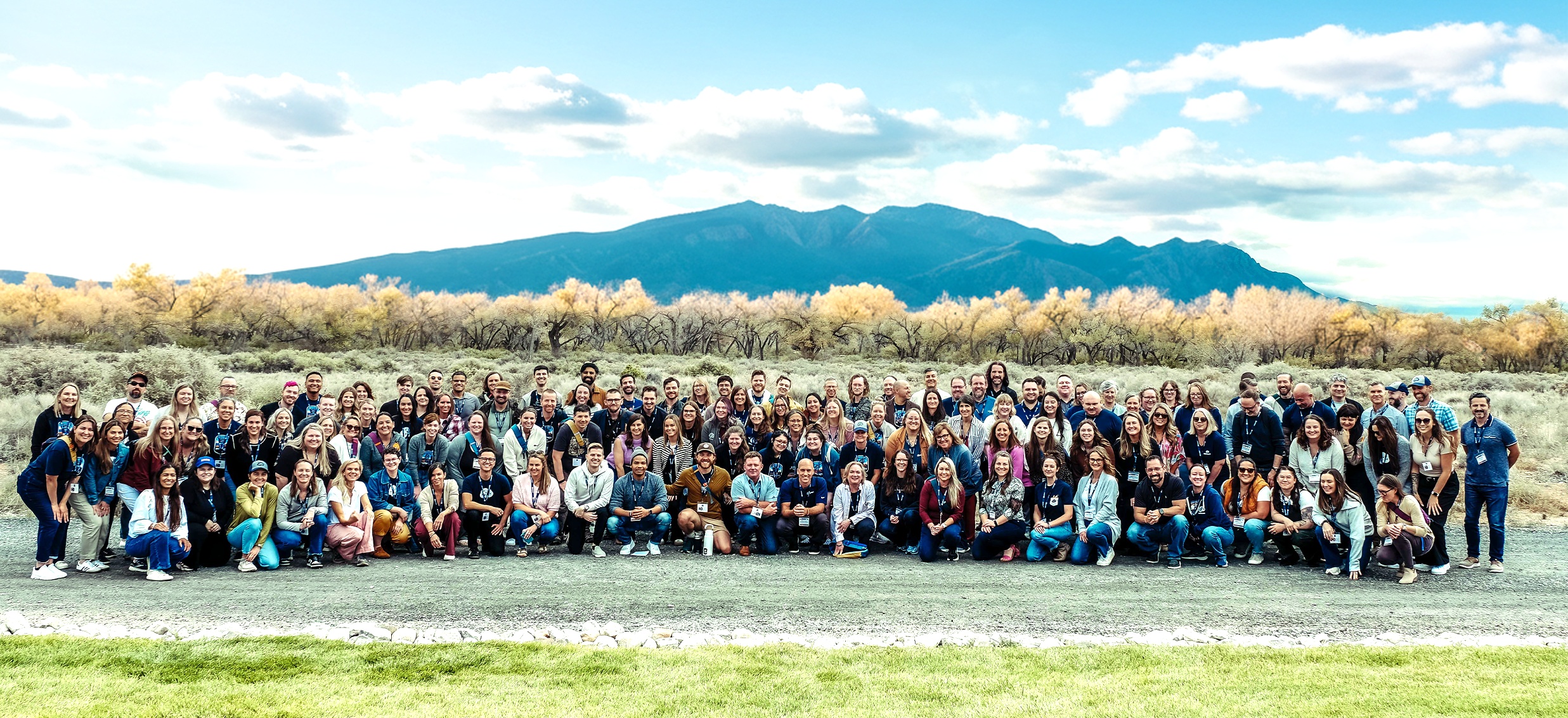 The Instinct team gathered outdoors for a group photograph with mountains behind them.