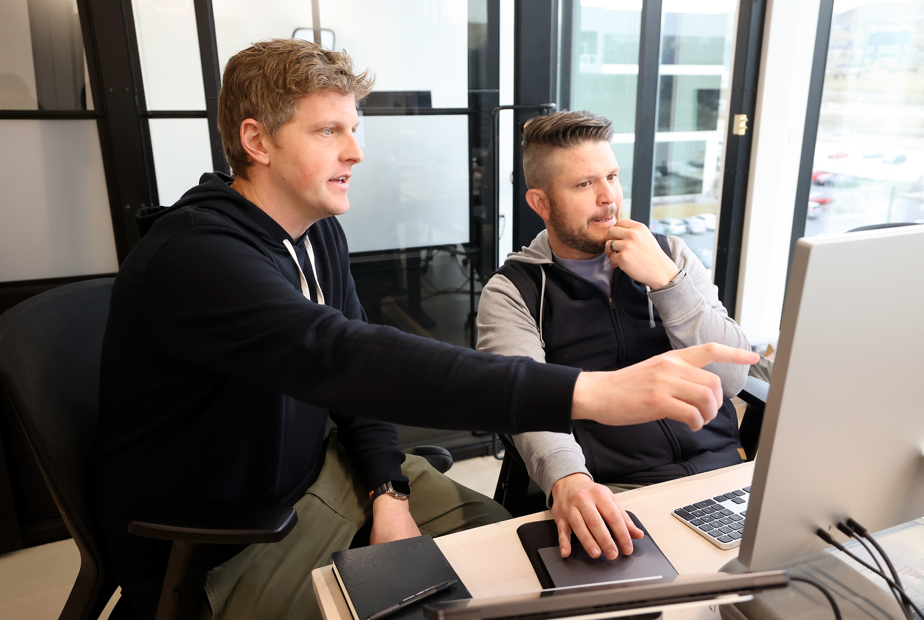 Caleb Hicks and SchoolAI chief technology officer Cahlan Sharp working together at a computer in SchoolAI's Lehi office