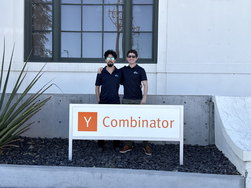 Salem Robotics co-founders Janak Panthi and Caleb Horan standing behind a Y Combinator sign