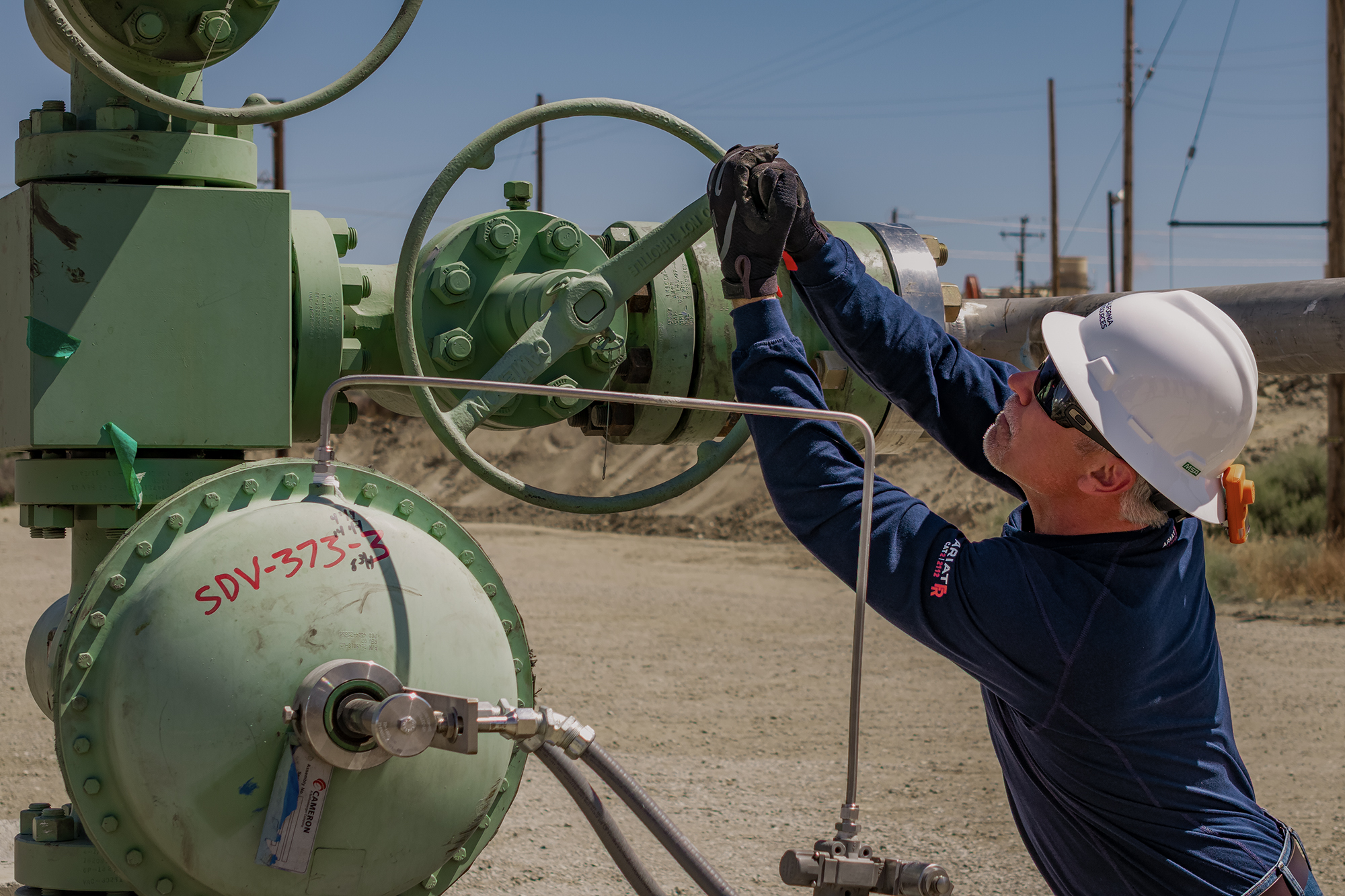 CRC worker turning a green wellhead valve at the Elk Hills carbon storage project