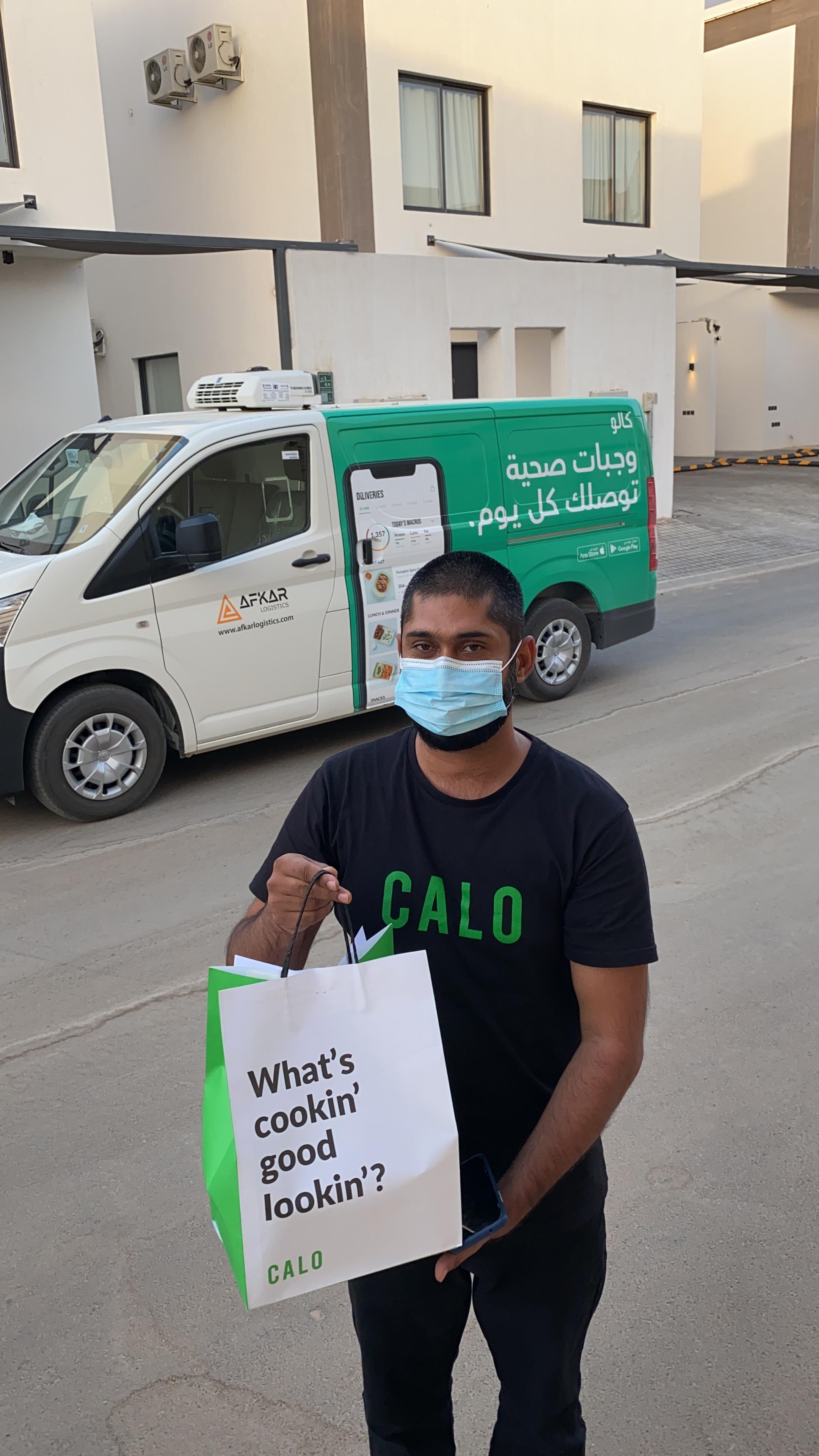 Ahmed Al Rawi carrying a Calo meal bag beside a branded delivery van