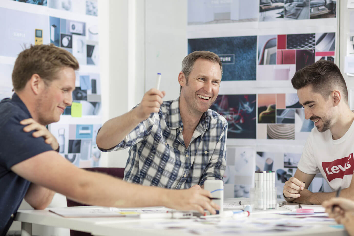 CDP designers exchanging ideas around a table of sketches and product models
