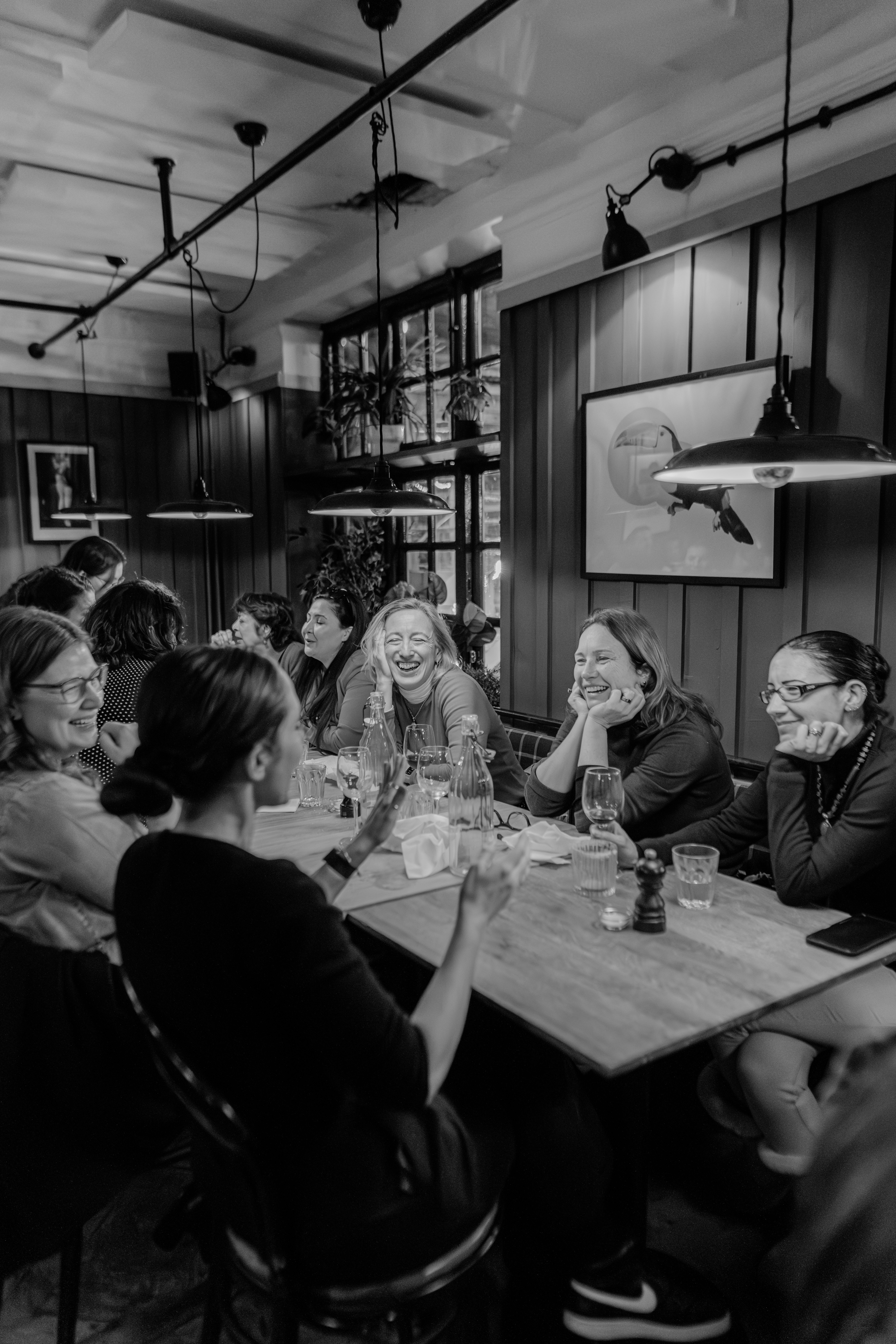 Women talking and laughing around a CFFN dinner table in a black-and-white photograph