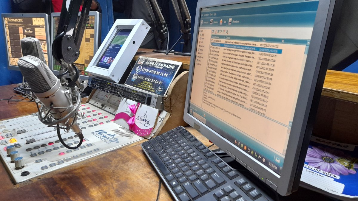 Microphone, mixing desk and computer screens inside an East African community radio studio