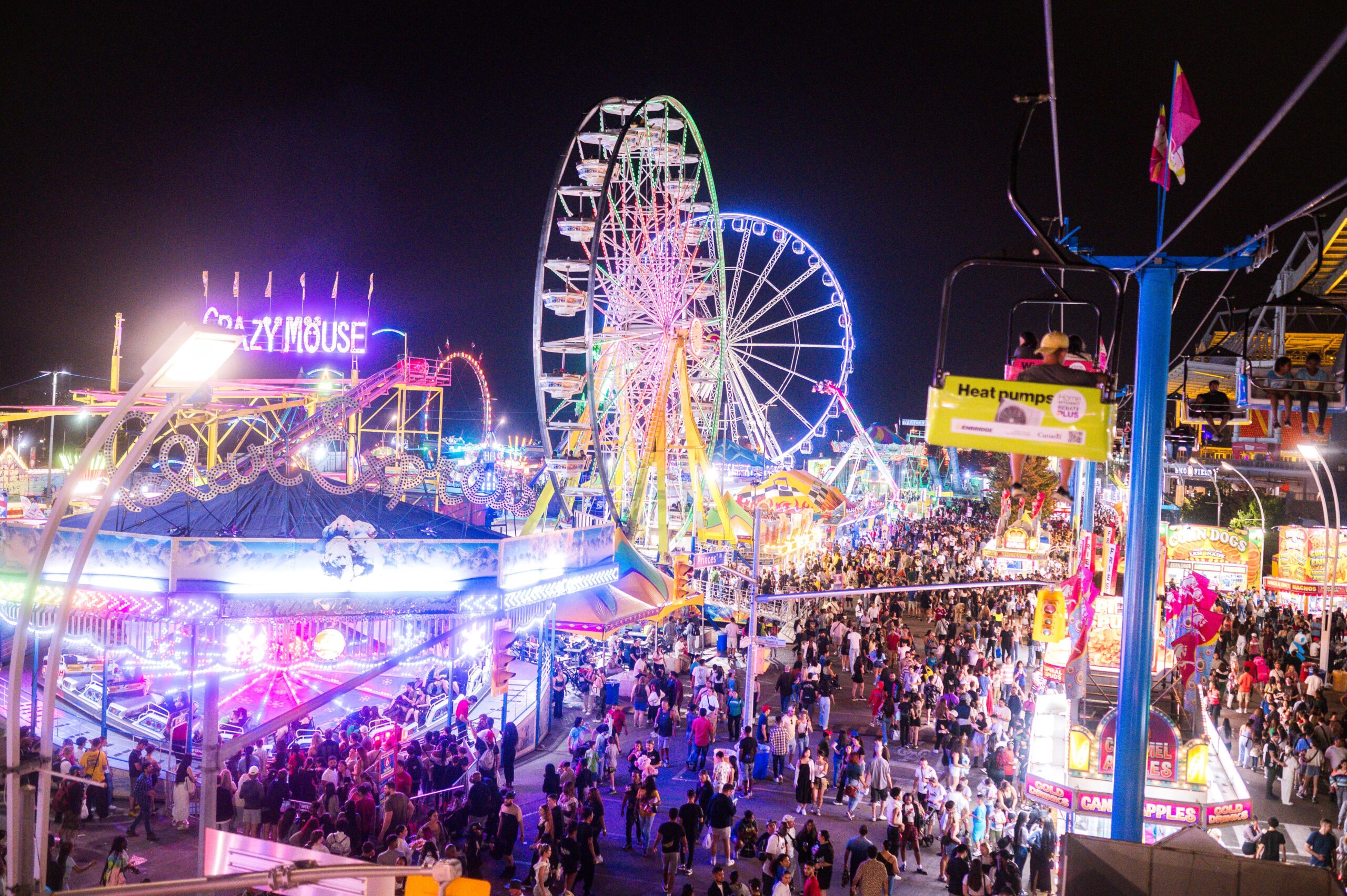 Crowds walking through the brightly lit CNE midway at night