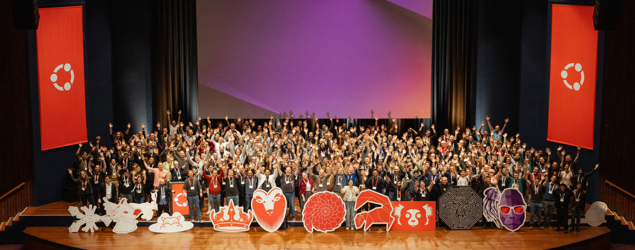 Ubuntu community members gathering on a stage with release mascot cutouts