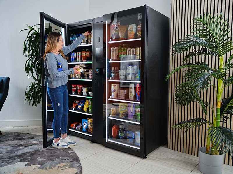 A shopper takes an item from an open Cantaloupe Smart Store cabinet