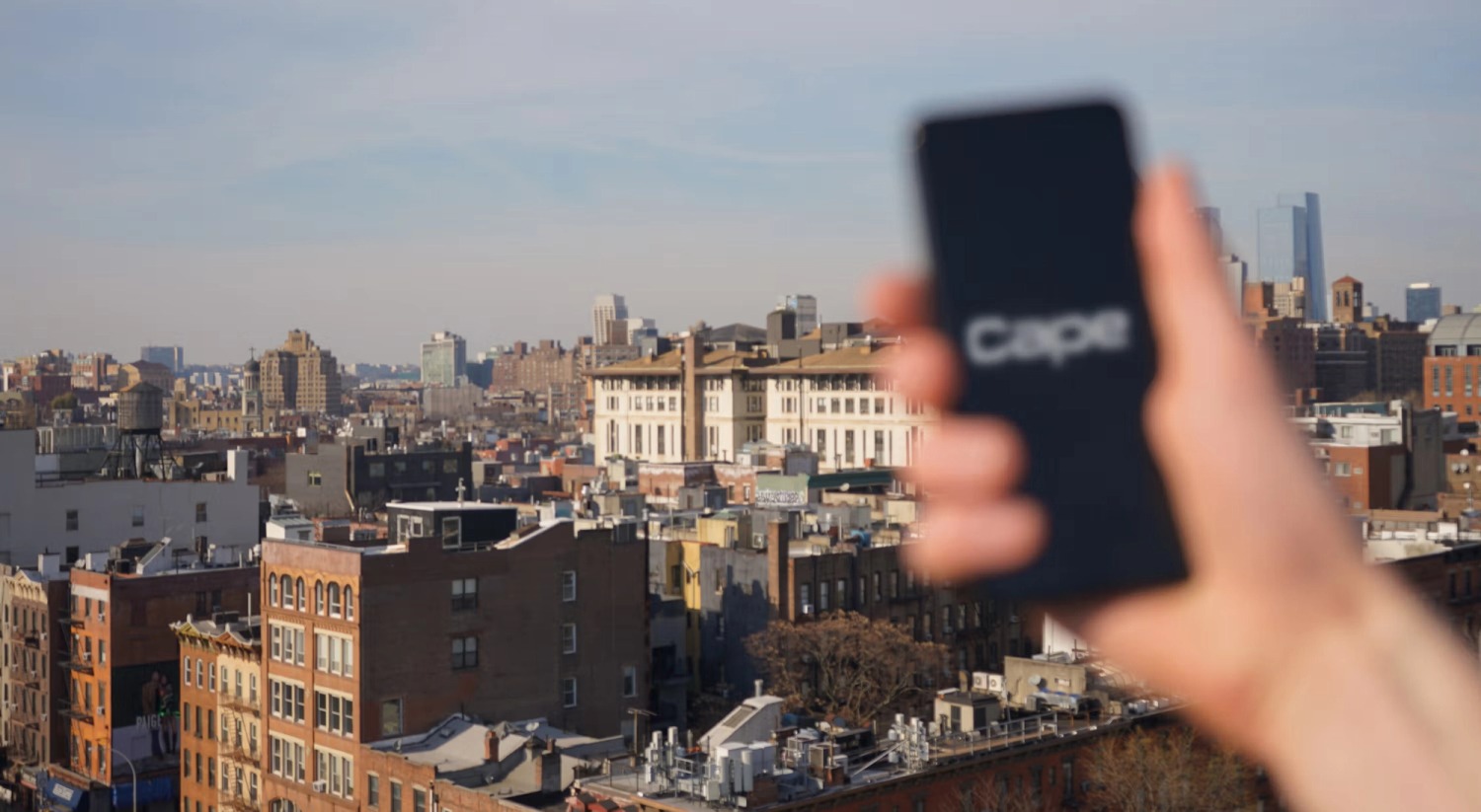 A hand holding a phone with the Cape name against a city skyline