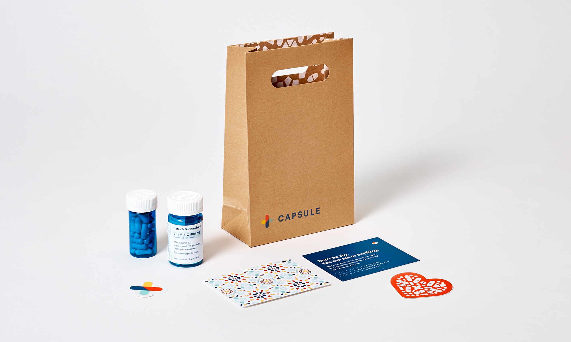 Capsule press photograph of blue medication bottles, a paper delivery bag and printed cards