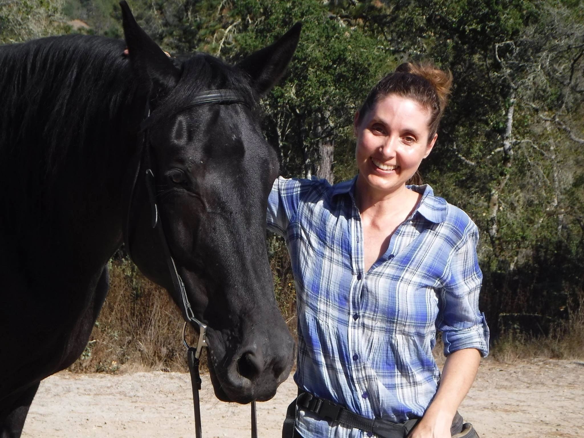 Cara Sloman outdoors beside a black horse