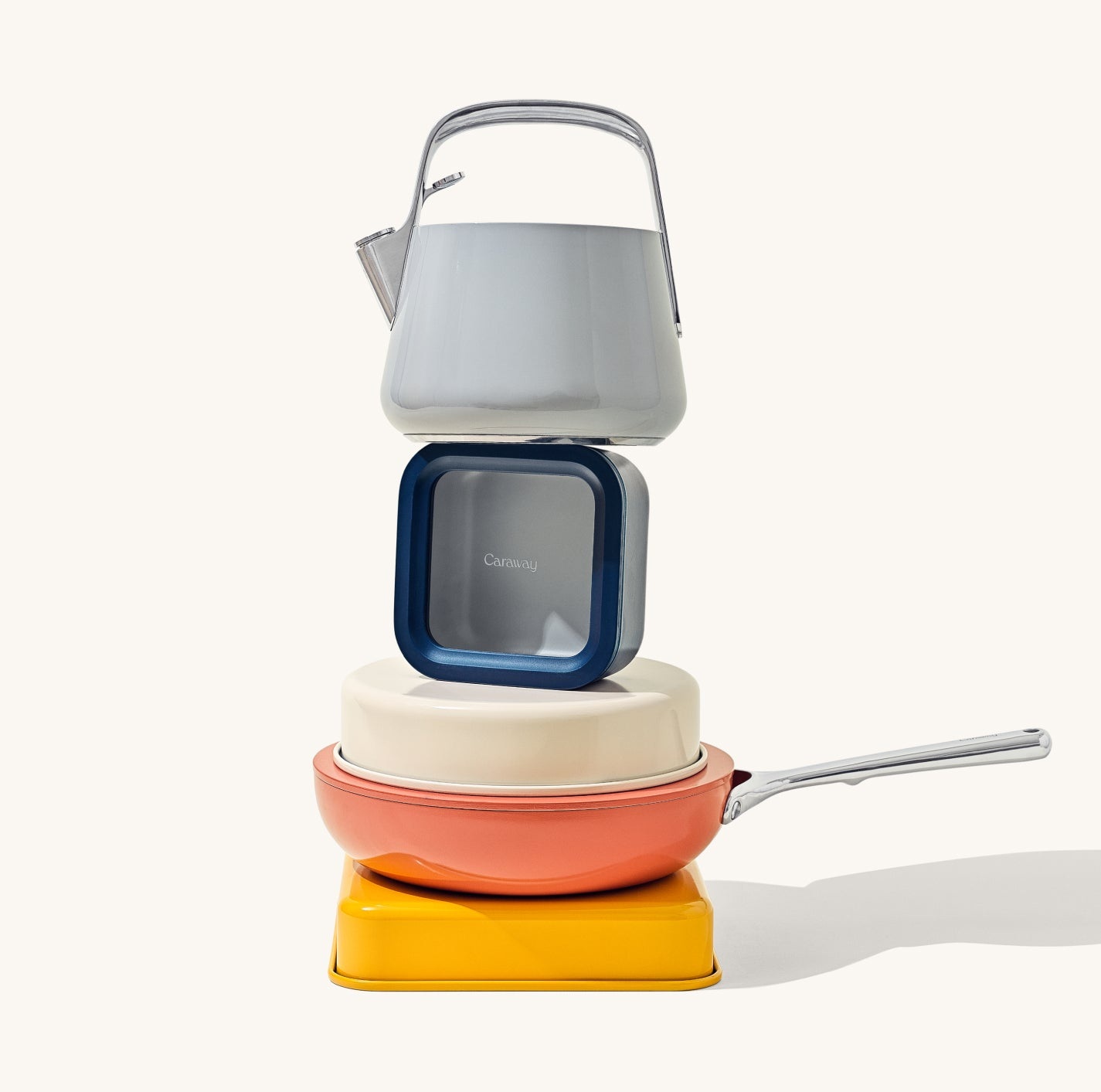 A kettle, food container and colorful pans balanced as a product sculpture