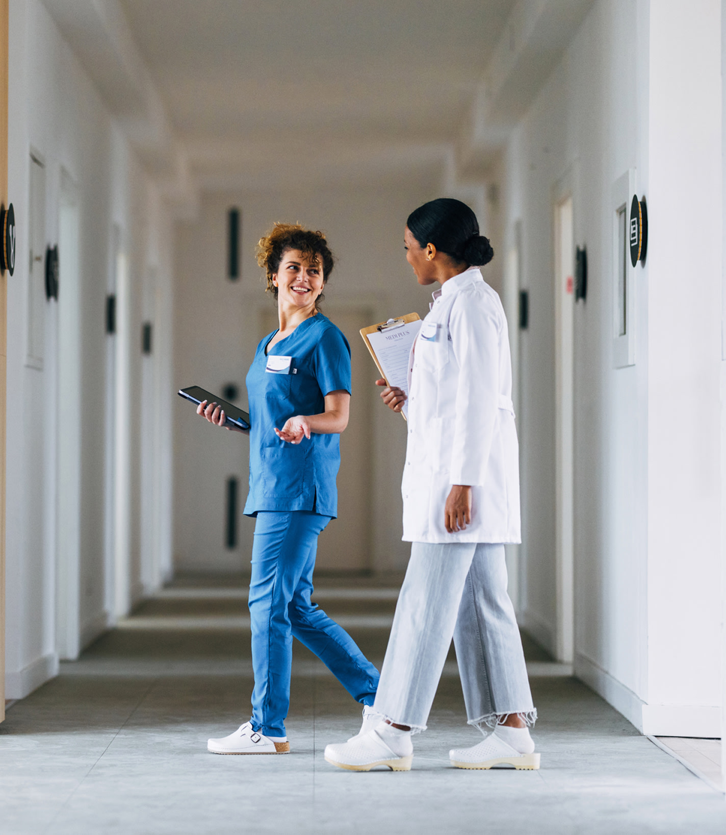 Two healthcare professionals talking in a hospital corridor