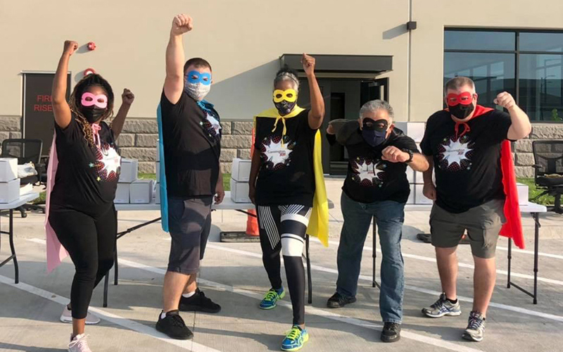Careington customer service team members wearing colorful superhero capes outside a building
