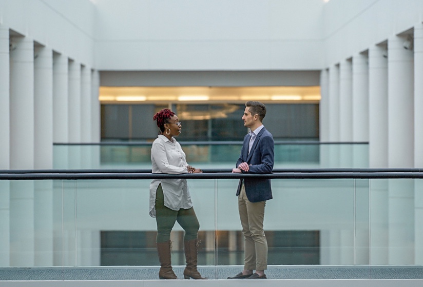 Ashley Mims and Joshua Yelverton talking beside an indoor balcony