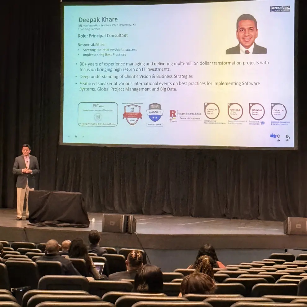 Deepak Khare speaking on a conference stage beneath a slide describing his role and experience