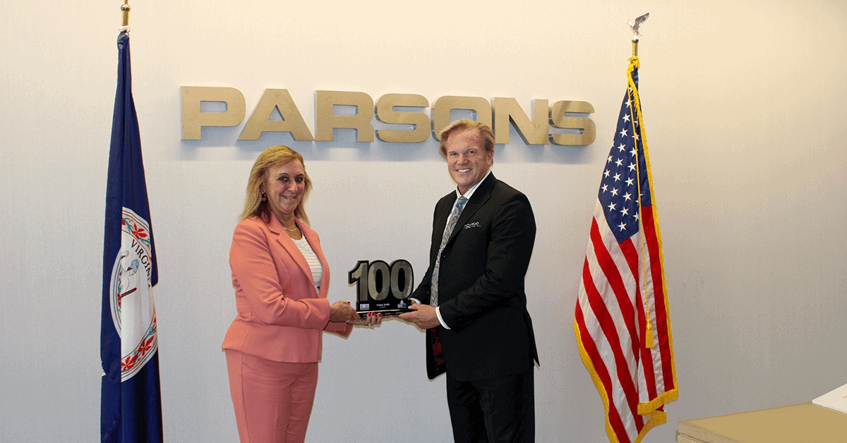 Carey Smith, left, and Jim Garrettson holding her Wash100 award at Parsons headquarters