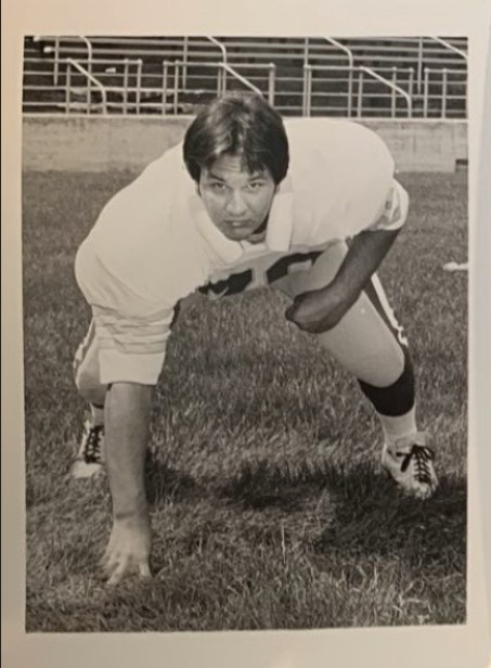 Archival photograph of Carl Allegretti crouching in football uniform