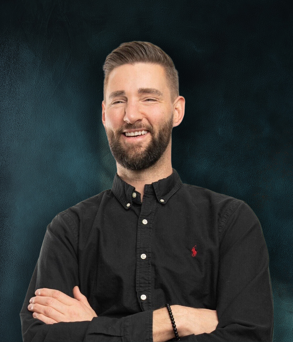 Carl Koussan-Price smiling in a black shirt against a dark textured background