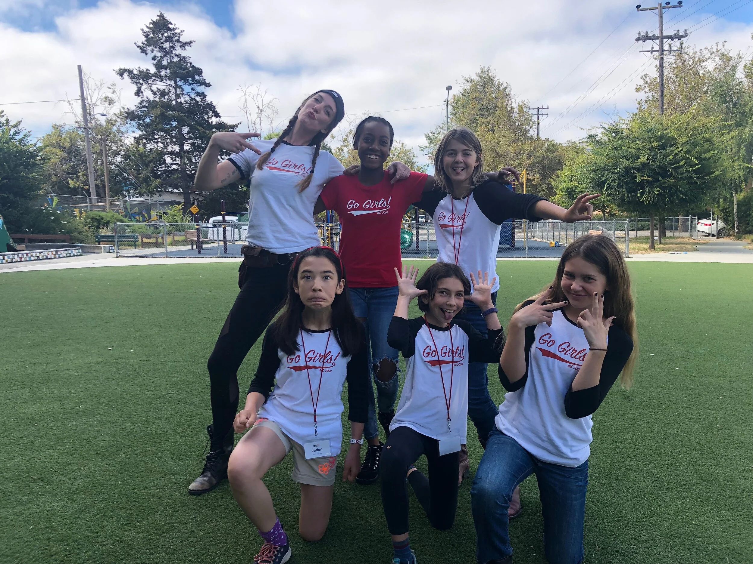 Go Girls participants and leaders making playful poses together on an Oakland field