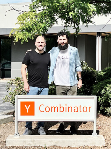 Two members of the Coba team standing beside a Y Combinator sign