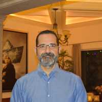 Carlos Tejeda in a casual blue shirt at an indoor gathering
