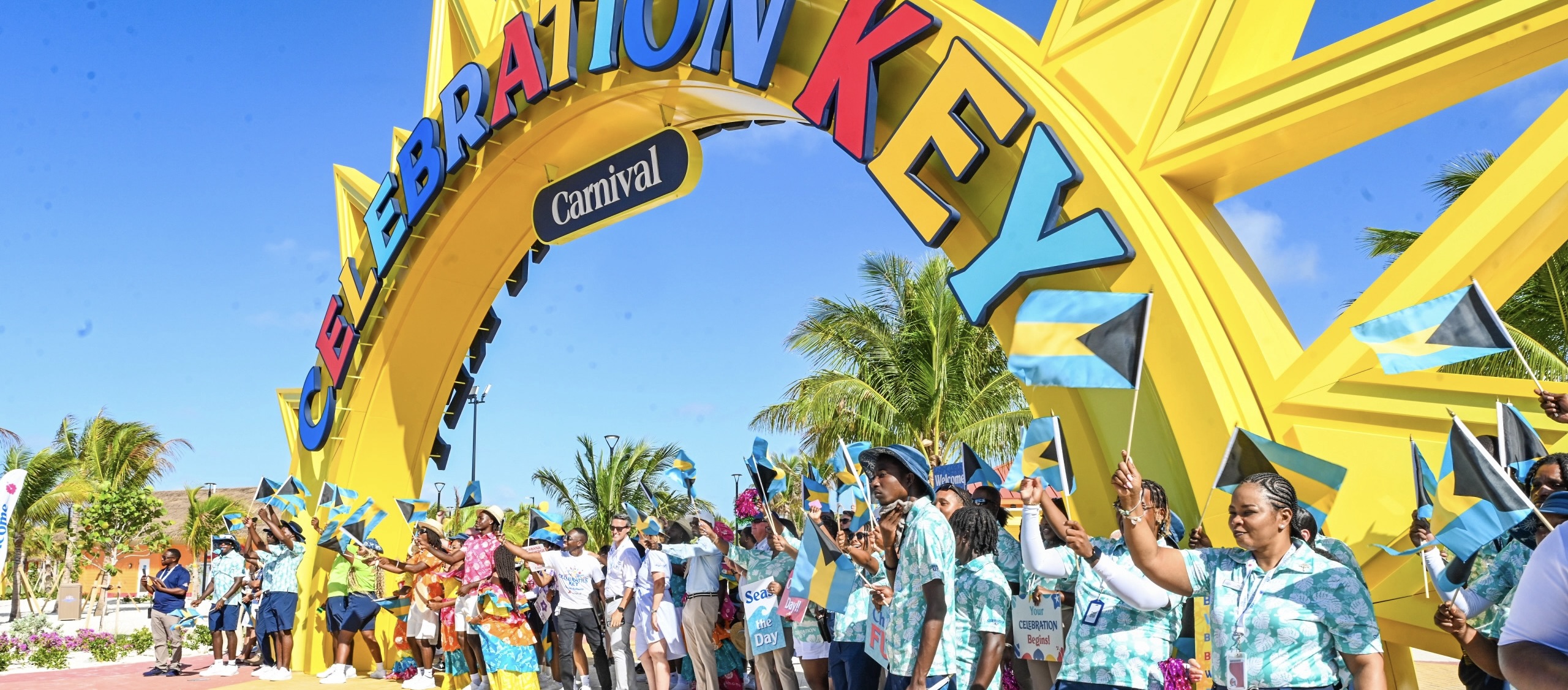 Bahamian flags wave beneath Celebration Key’s yellow entrance arch on opening day
