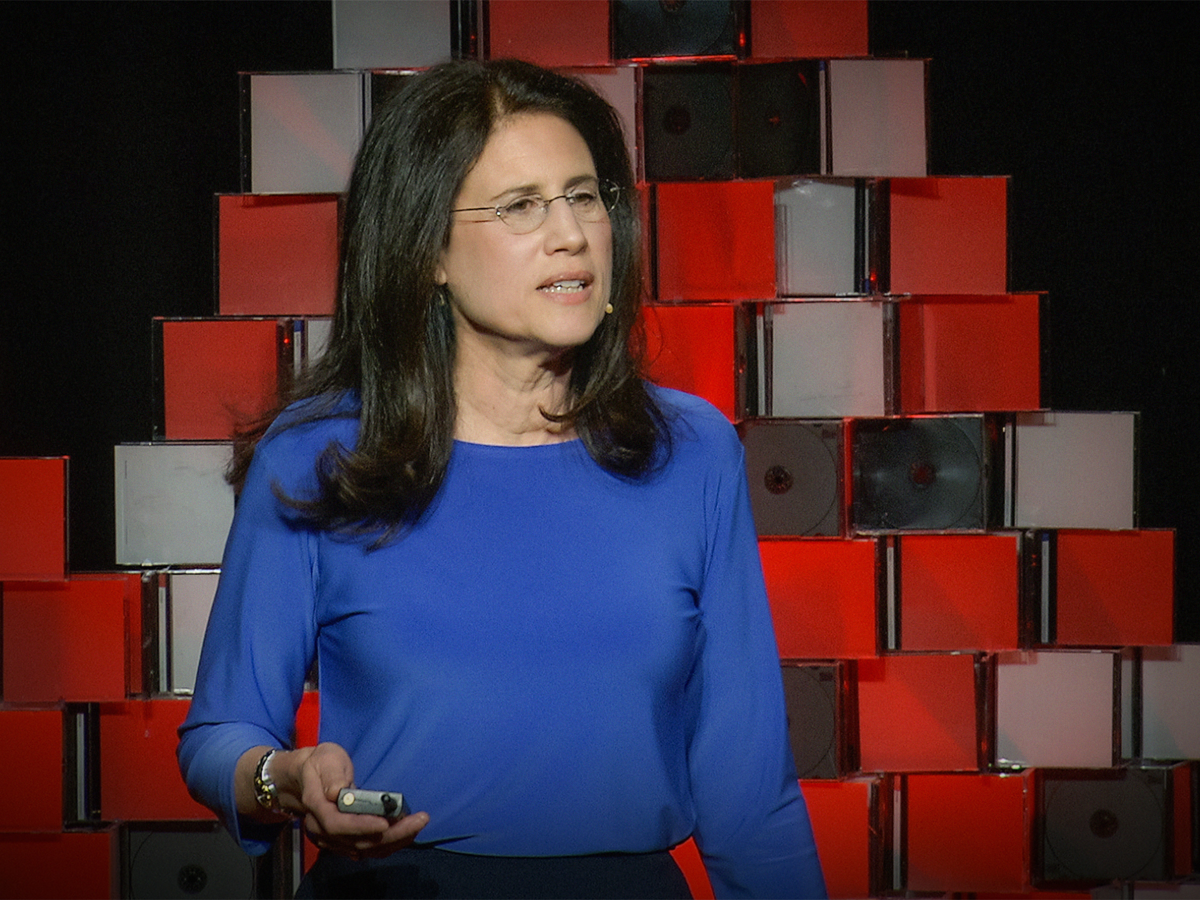 Carol Fishman Cohen in blue, speaking on the TEDxBeaconStreet stage