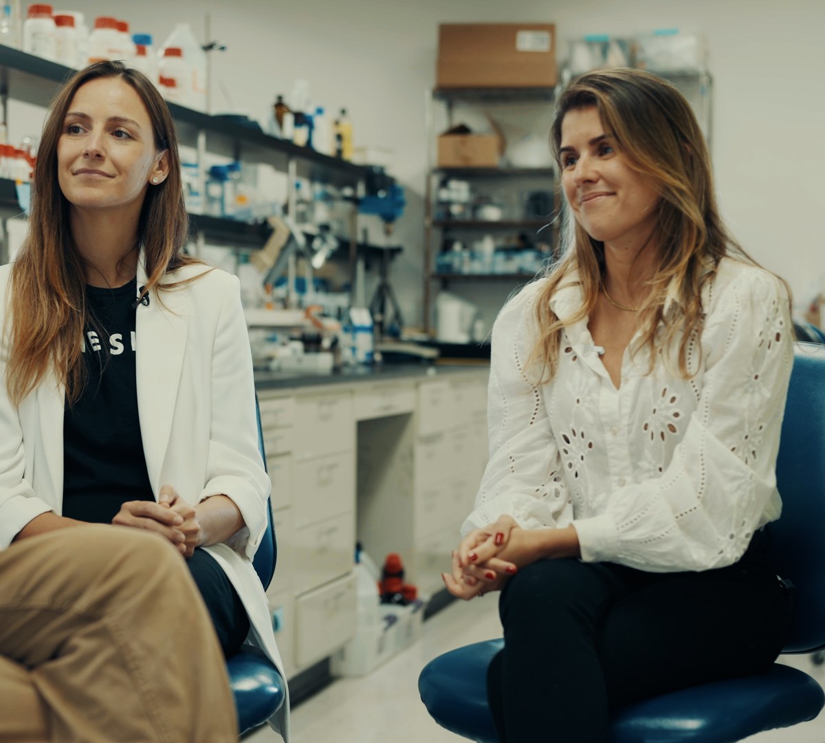 Carolina Reis Oliveira and Alessandra Zonari seated together in the OneSkin laboratory