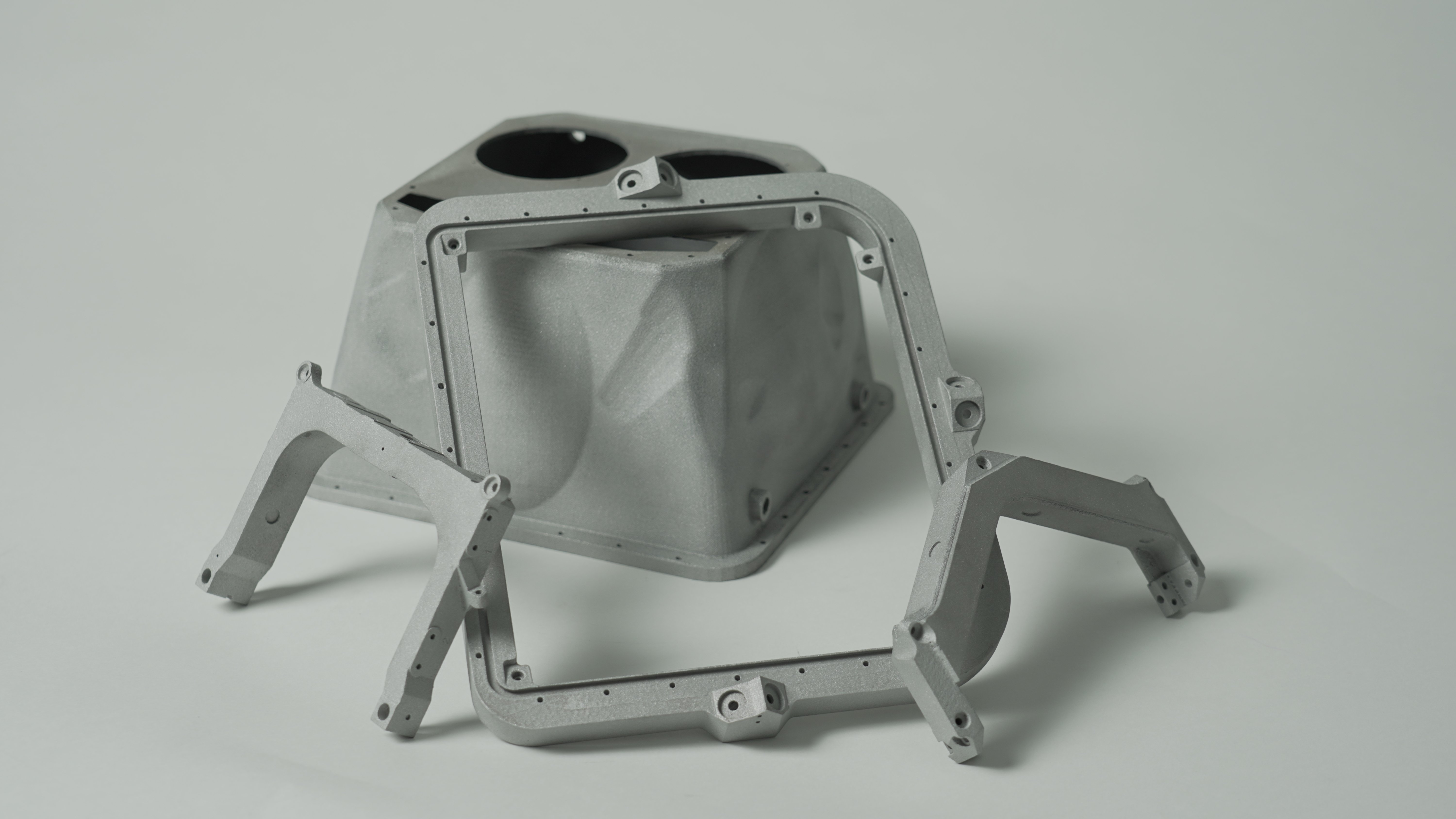 Thin-walled titanium PIXL instrument housing and supports displayed together