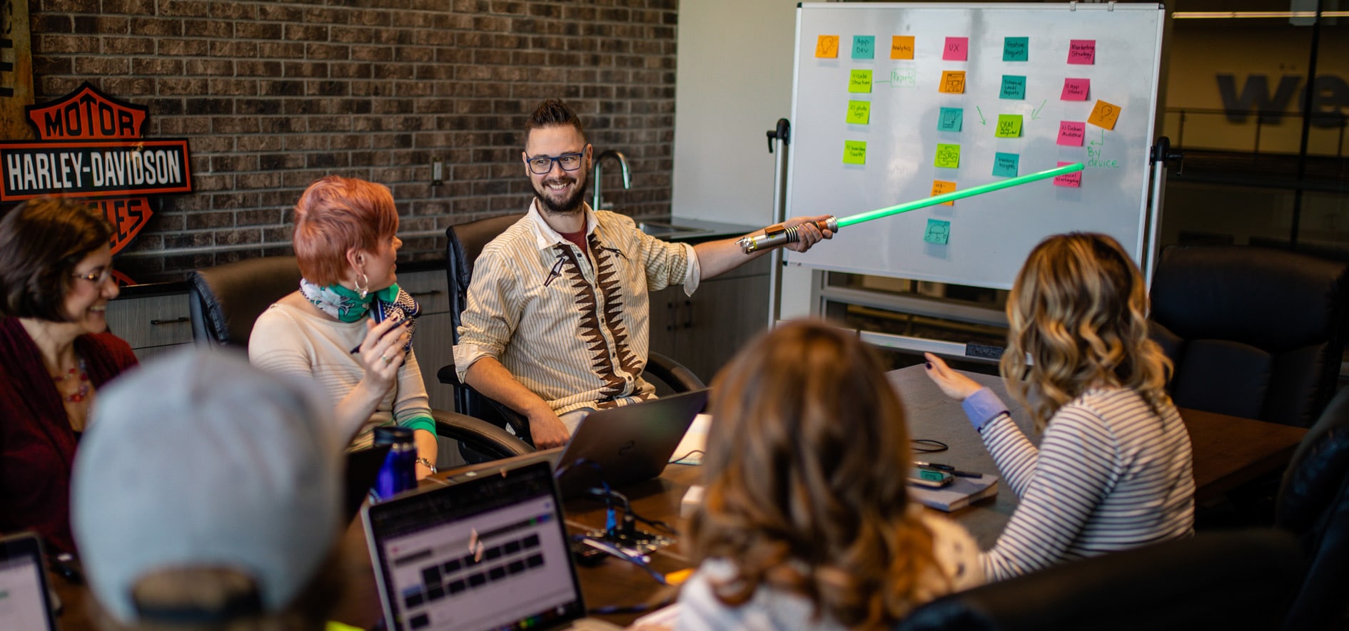Carsforsale.com coworkers in a meeting where a participant points at a whiteboard with a green lightsaber