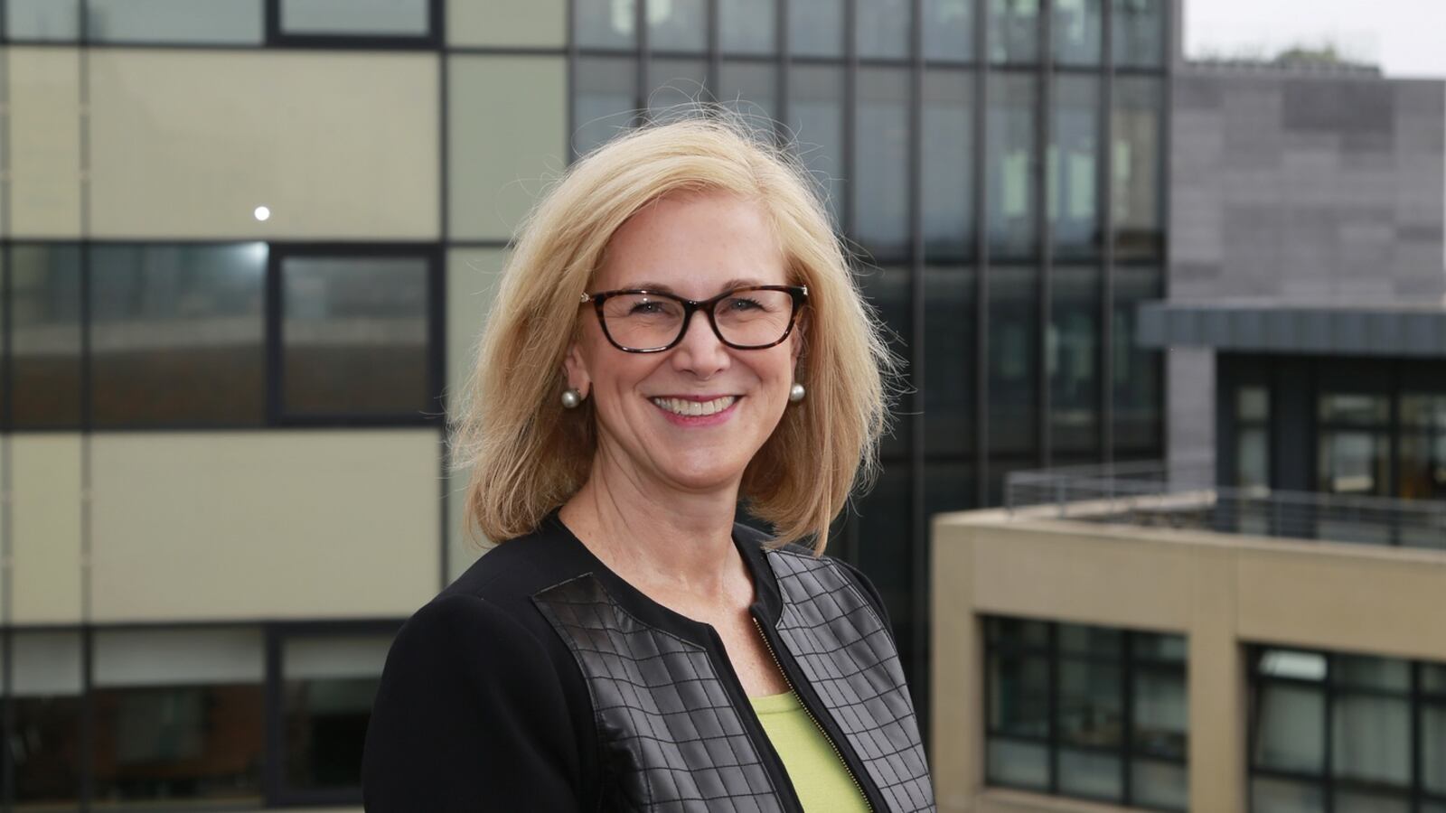 Cary Grace smiling outdoors in front of a modern building