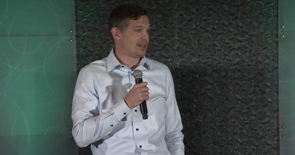 Casey DeLoach holding a microphone during his Celebration of Generosity presentation