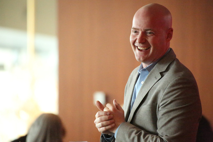 Casey Graham smiling while speaking, wearing a grey blazer