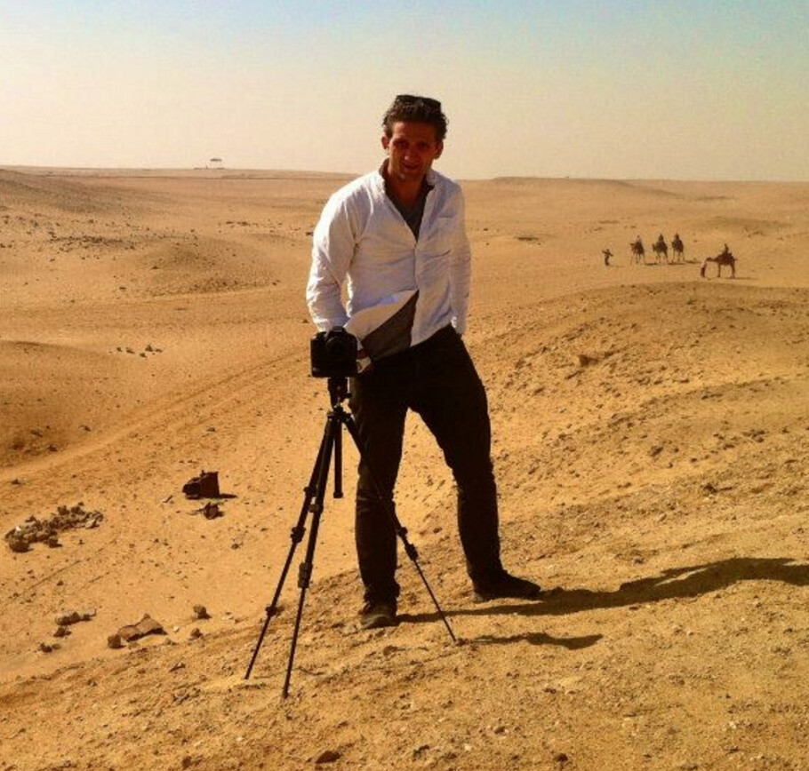 Casey Neistat standing beside a camera on a tripod in a desert landscape