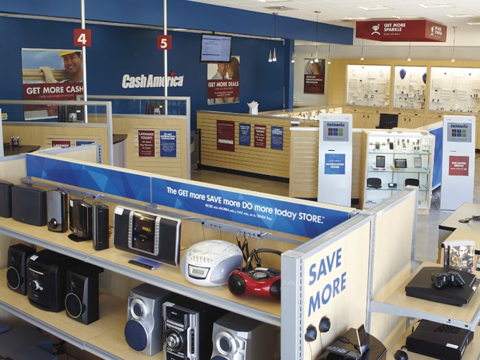 Electronics shelves, numbered service counters and illuminated jewelry cases inside a Cash America Pawn store