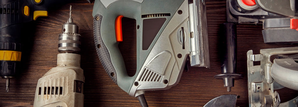 Power drills and other used tools arranged on a wooden surface in a FirstCash promotional photograph