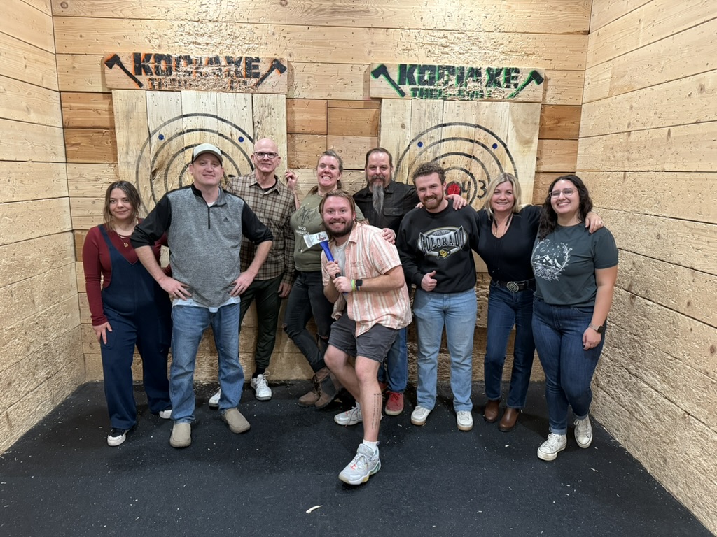 Sky Peak Technologies team members smiling during an axe-throwing outing