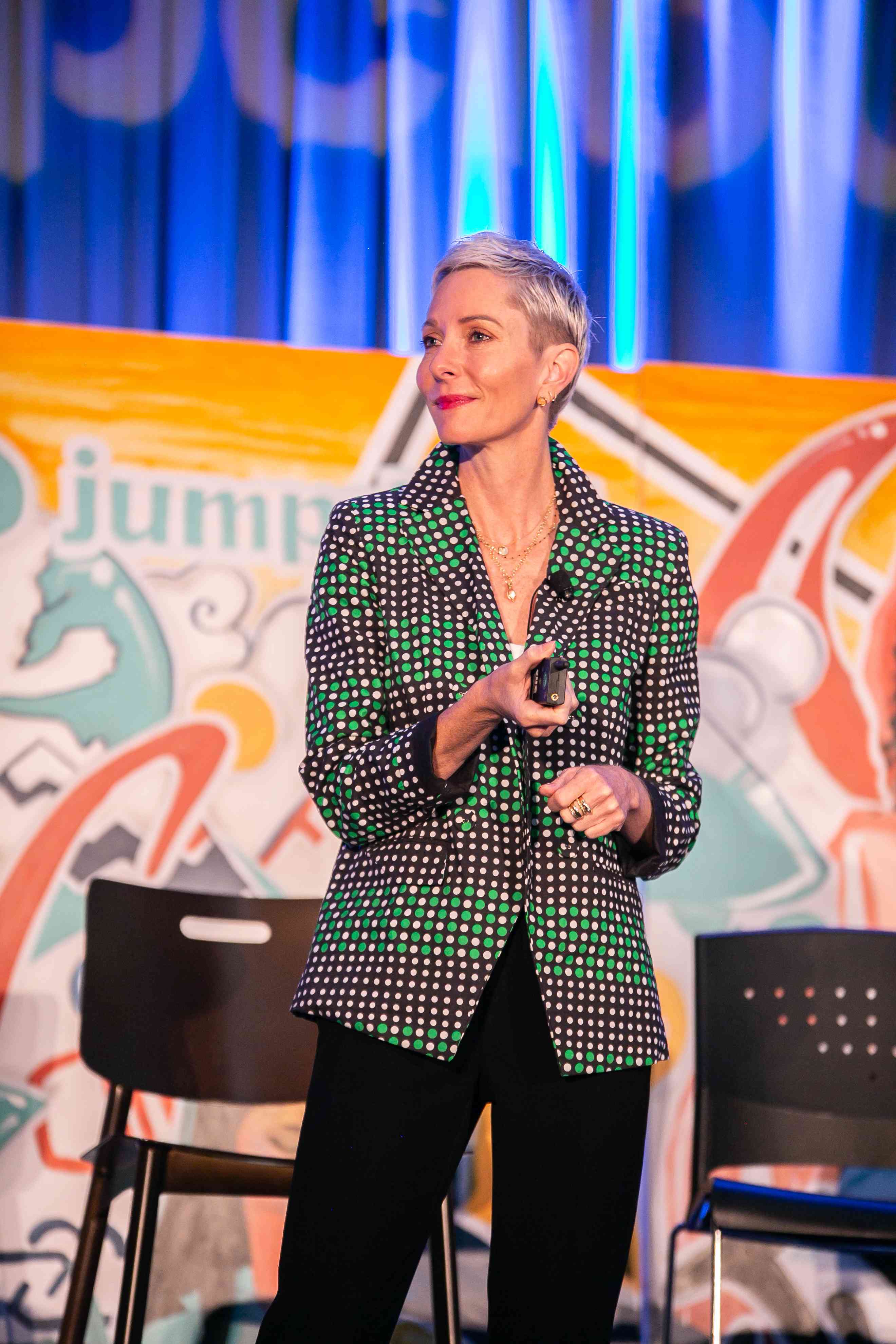 Cate Lochead speaking onstage in a patterned jacket