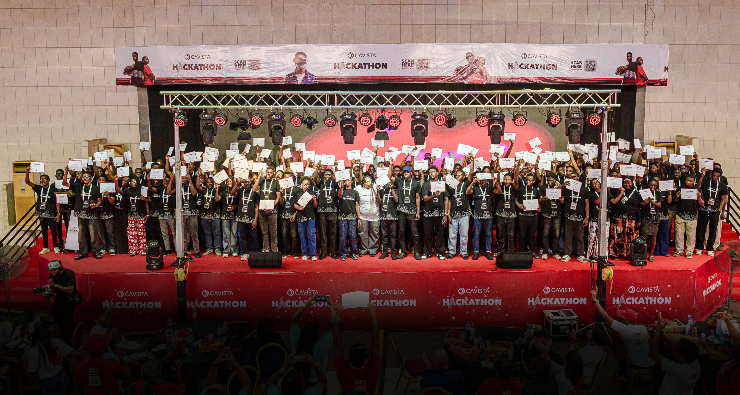 A large group of Cavista hackathon participants holding certificates on a stage