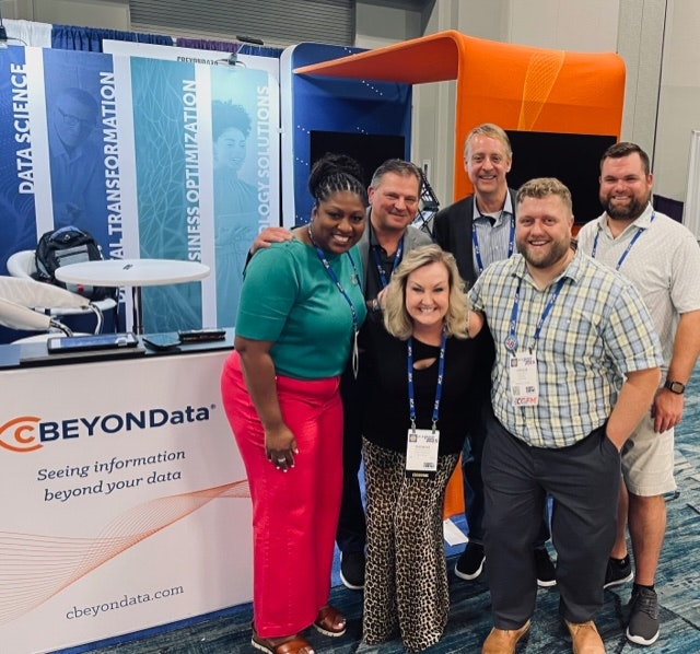 Six cBEYONData team members gathered beside their conference booth