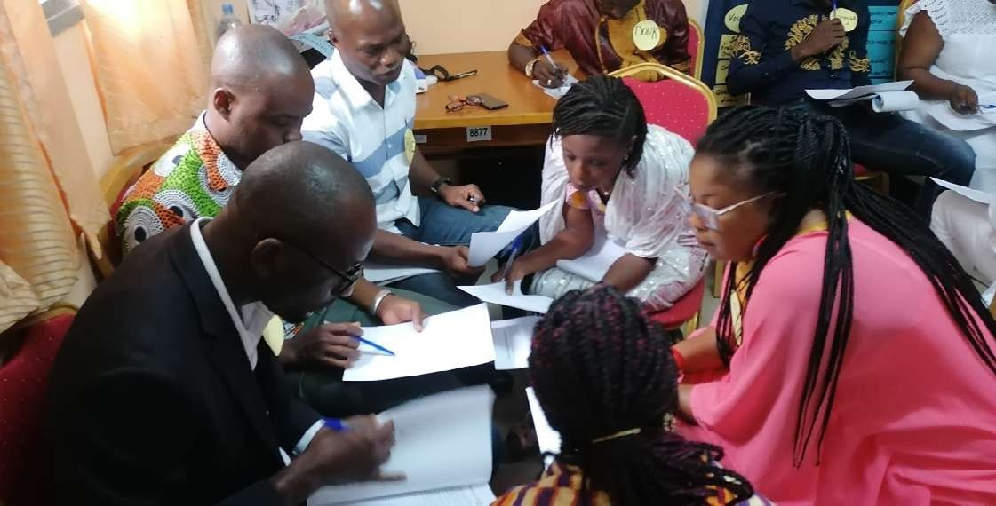 Participants work together with notebooks during CEFE trainer development in Côte d’Ivoire
