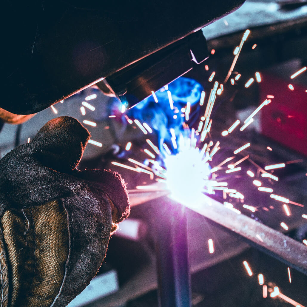 Close view of industrial welding with bright sparks and protective gloves